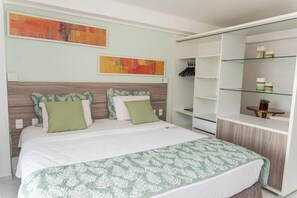 A bedroom with a bed, a wardrobe, and two abstract paintings on the wall. - Bright Suite Unforgettable Beach Retreats - Beachfront with Rooftop Pool (Paraíba)