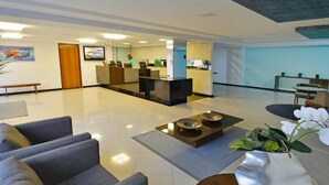 Eine moderne Lobby mit Empfangstresen, Sitzgelegenheiten und einer Zierpflanze.