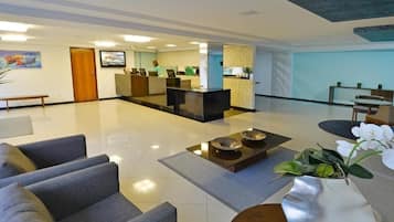 A modern lobby with a reception desk, seating area, and a decorative plant.