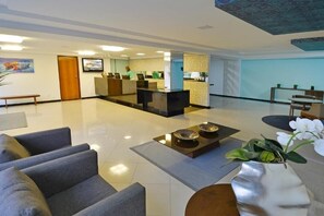 A modern lobby with a reception desk, seating area, and a decorative plant. - Bright Suite Unforgettable Beach Retreats - Beachfront with Rooftop Pool (Paraíba)