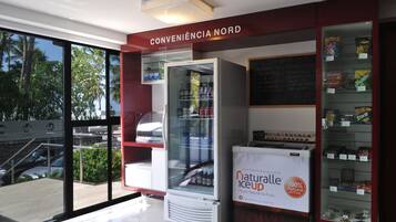 A convenience store with a glass display case, a freezer, and a vending machine labeled "natural ice up."