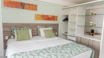 A bedroom with a bed, a wardrobe, and two abstract paintings on the wall.