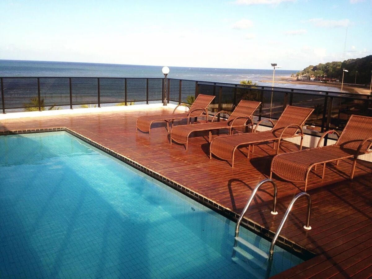 A swimming pool with lounge chairs and a view of the sea.