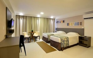 A hotel room with two beds, a desk, a chair, a TV, and a window with curtains. - Elegant Suite 3.7 Miles Away From Ponta do Seixa - with Rooftop Swimming Pool (Paraíba)