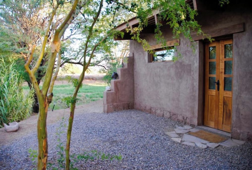 A rustic building with a wooden door and a gravel driveway.