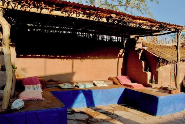 A traditional outdoor seating area with stone steps and a thatched roof structure.
