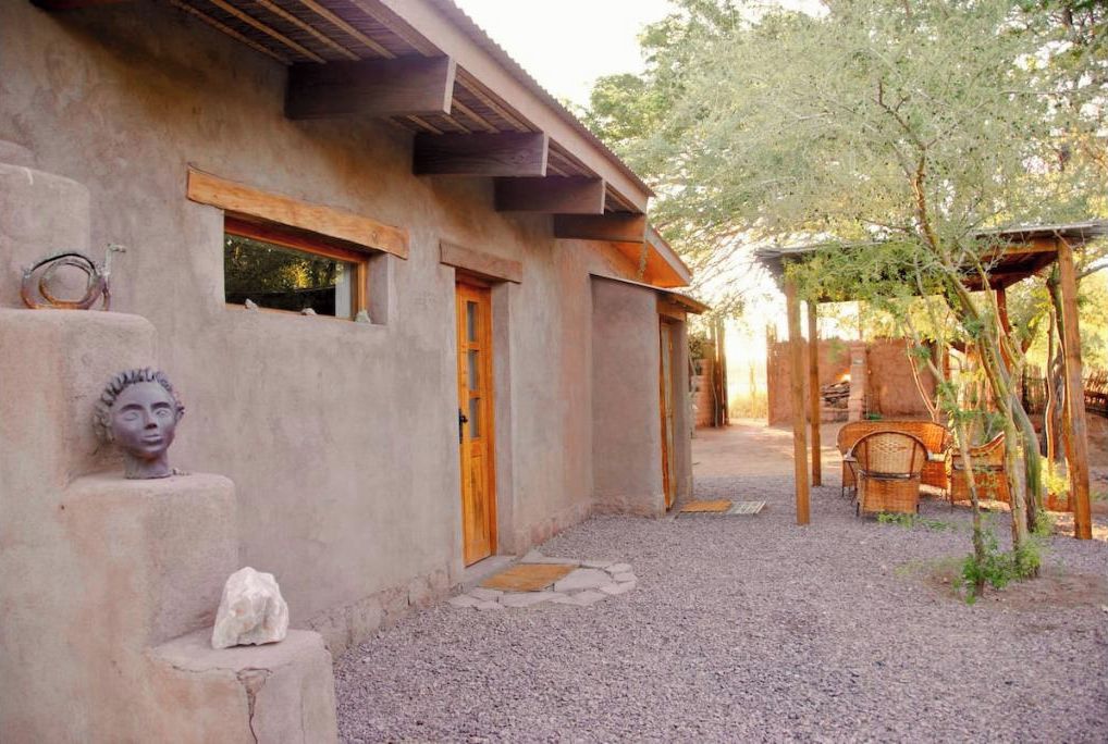A rustic building with a gravel driveway, wooden door, and a small window.