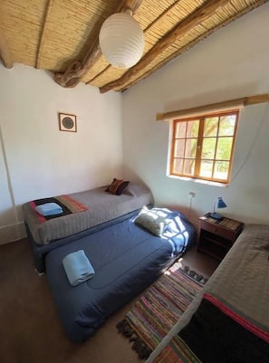 A room with two beds, a window, a lamp, and a small table.