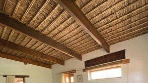 Una habitación con una cama, techo de madera, una ventana y un banco.