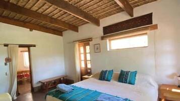 A room with a bed, a wooden ceiling, a window, and a bench.