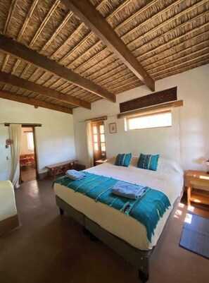 Een kamer met een bed, houten plafond, een raam en een bank.