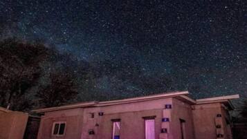 A building with a flat roof and multiple windows, surrounded by a gravel area under a starry night sky.