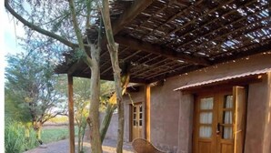 Un espacio de estar al aire libre de estilo rústico con muebles de mimbre y una pérgola.