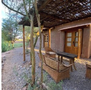 Een rustieke buitenruimte met rieten meubels en een pergola.