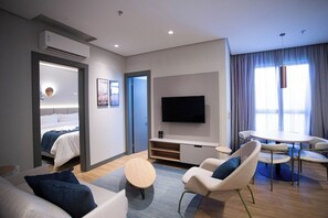 Une chambre d’hôtel moderne équipée d’un lit, d’une télévision, d’un coin repas avec des chaises et d’une petite table.