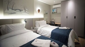 Una habitación de hotel con dos camas, un escritorio y un armario.