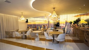 Un restaurante moderno con mesas y sillas redondas, un mural con un paisaje urbano en la pared y vistas del horizonte de la ciudad.