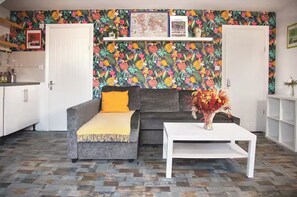 A living room with a grey sofa, a white coffee table, and a floral wallpaper. - 3 Bed Flat - 1 Min Walk Underground (London)