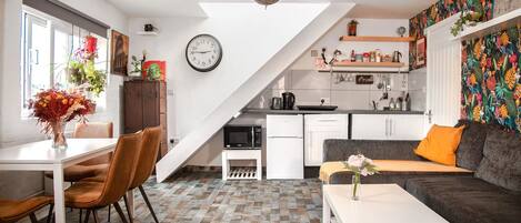 A modern living space with a dining area, kitchen, and a staircase.