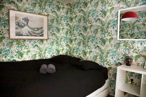 A room with a bed, a wall-mounted picture, a red lamp, and a shelf with a vase. - 3 Bed Flat - 1 Min Walk Underground (London)