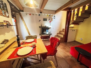 Ein Essbereich mit einem Holztisch für zwei Personen, einem Kamin und einer Treppe, die zu einer oberen Ebene führt.