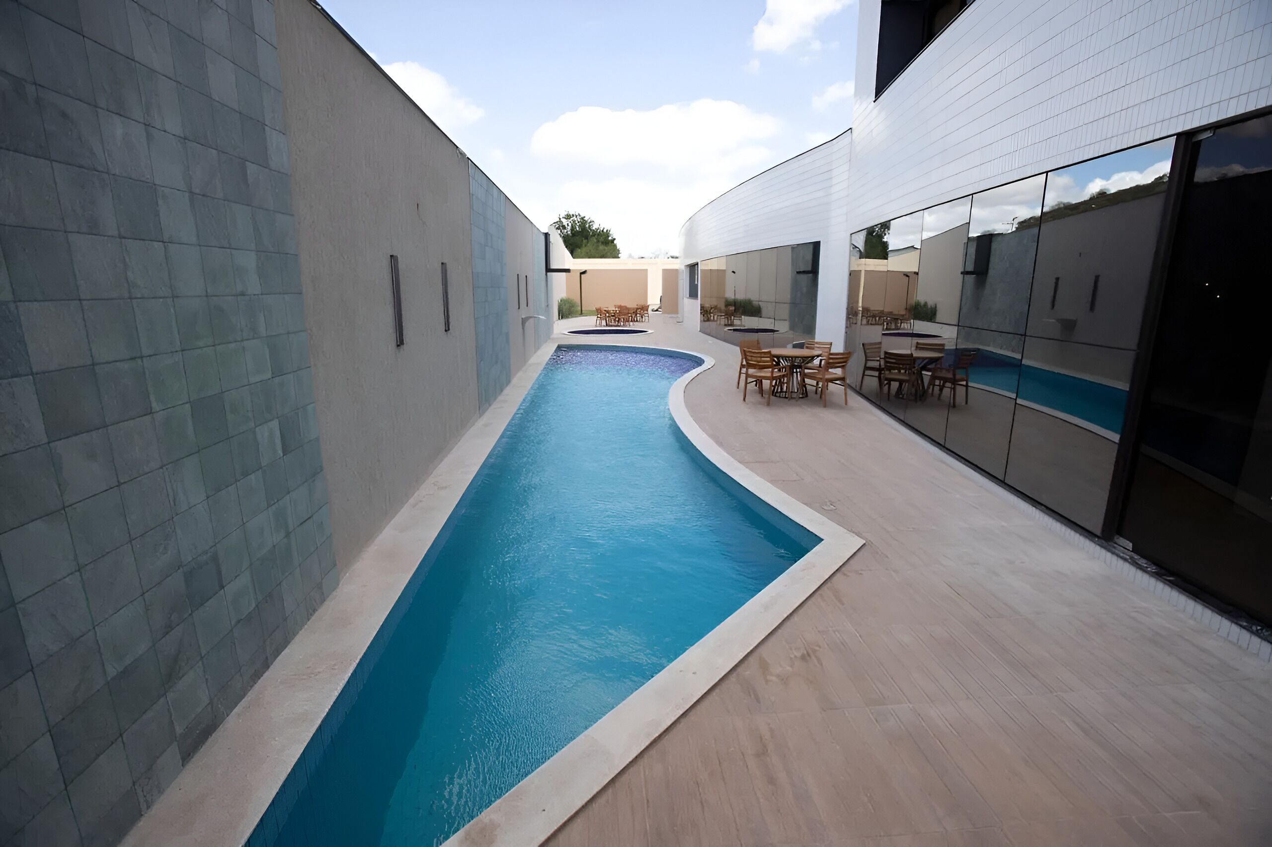 Um edifício moderno com piscina, área de estar externa e janelas amplas.