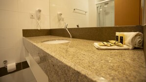 A bathroom with a granite countertop, a sink, a towel, and a mirror. - Stylish Room with Balcony and Buffet Breakfast – Near Main Attractions (Pernambuco)