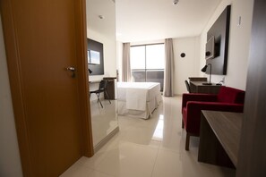 Ett hotellrum med en säng, ett skrivbord, en stol och en tv.