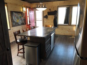 A kitchen with a granite countertop, stainless steel appliances, wooden walls, and a map decoration. - Glacier Aurora - Stargazing Wonder overlooking the Forest and the East Rockies (Babb)