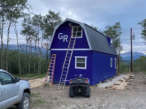 A blue house with a ladder and an ATV parked in front. - Glacier Aurora - Stargazing Wonder overlooking the Forest and the East Rockies (Babb)