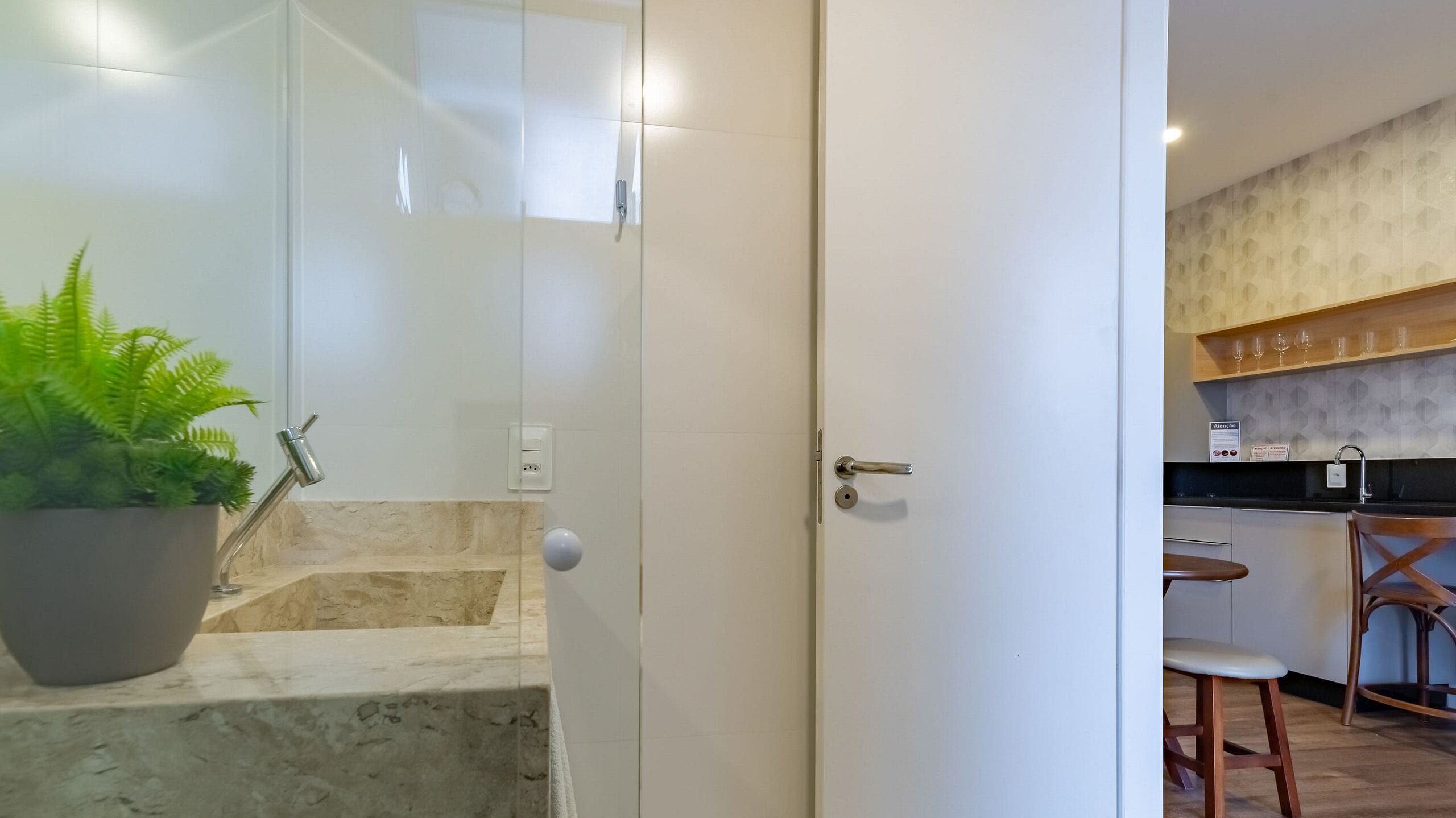 Una cocina moderna con barra, una planta en maceta y una escalera que lleva a un dormitorio.