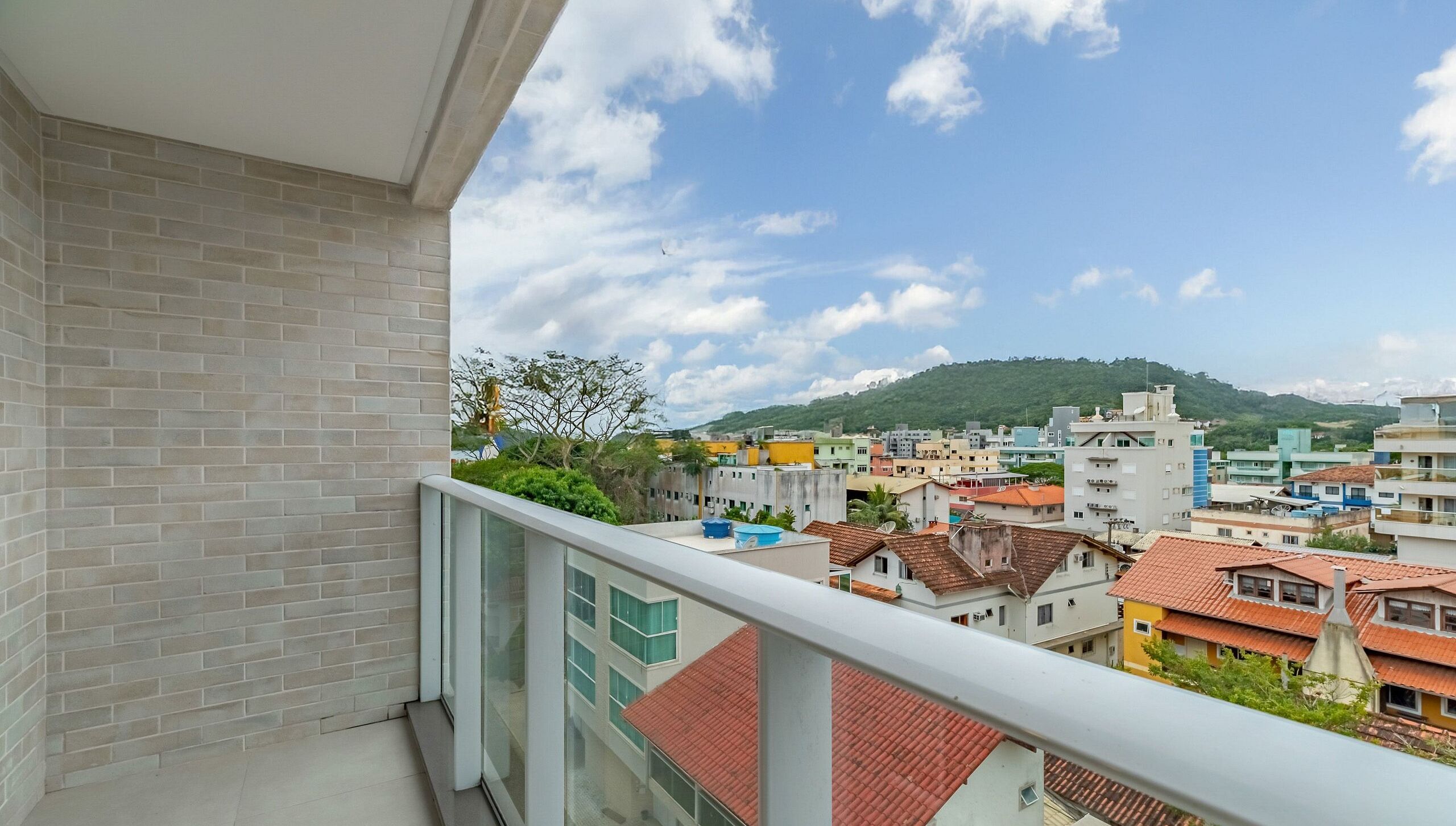 A balcony with a view of a cityscape, including buildings and a hill in the distance.