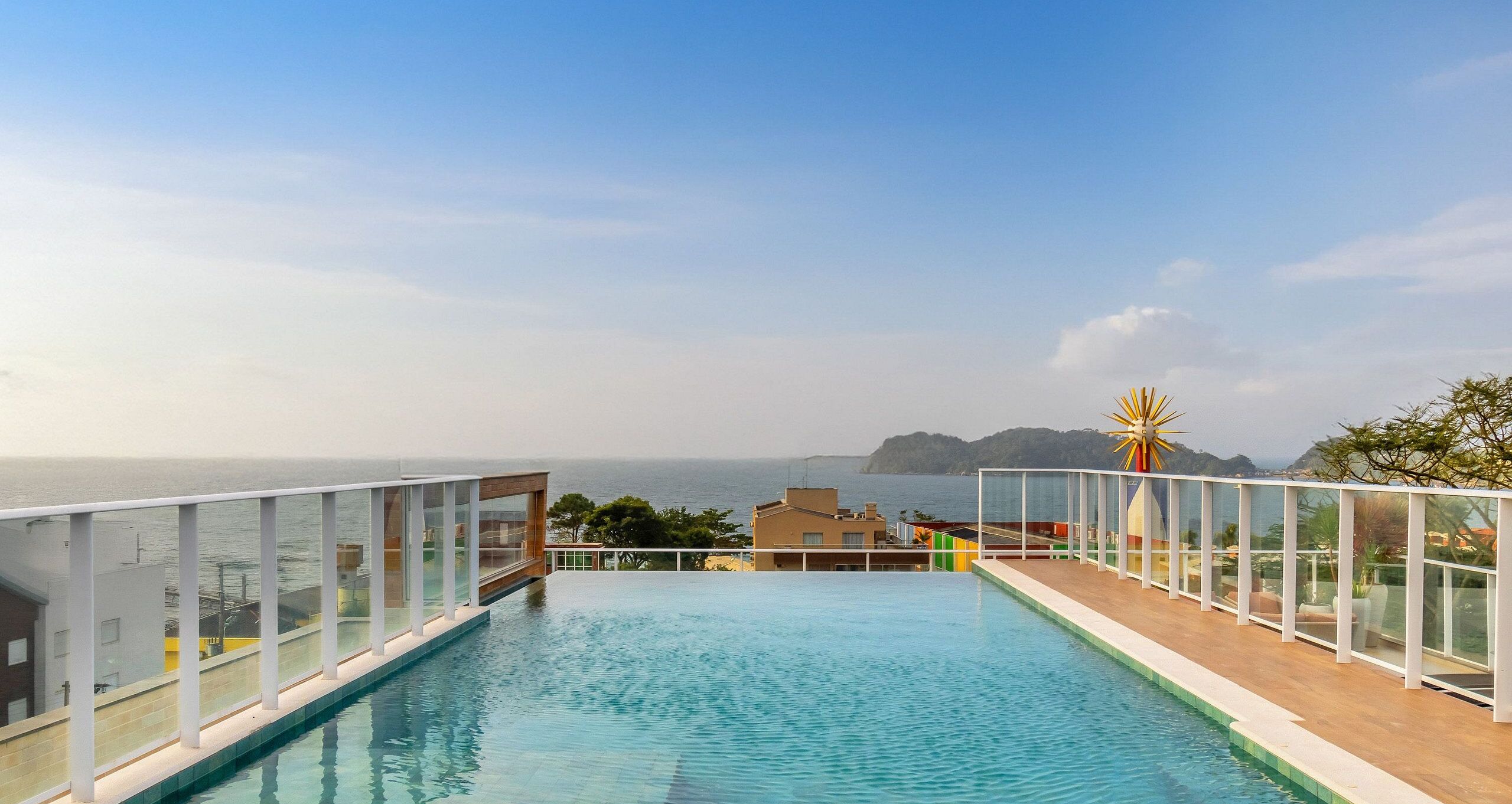 Una piscina infinita en la azotea con vistas despejadas al mar y a la costa lejana.