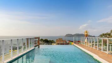 Una piscina infinita en la azotea con vistas despejadas al mar y a la costa lejana.