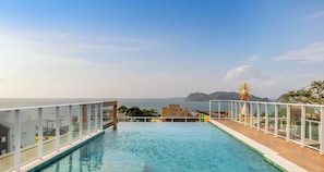 Una piscina infinita en la azotea con vistas despejadas al mar y a la costa lejana.