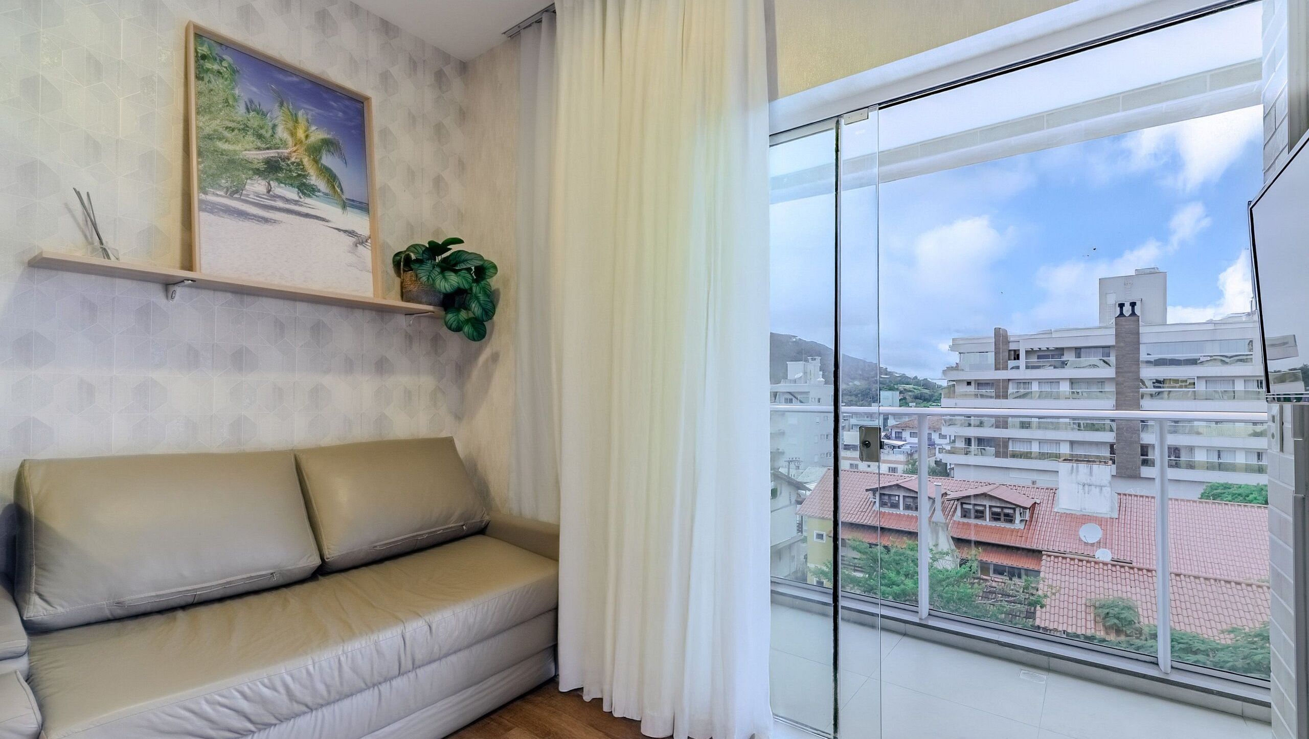 A living room with a sofa, a painting, and a plant.