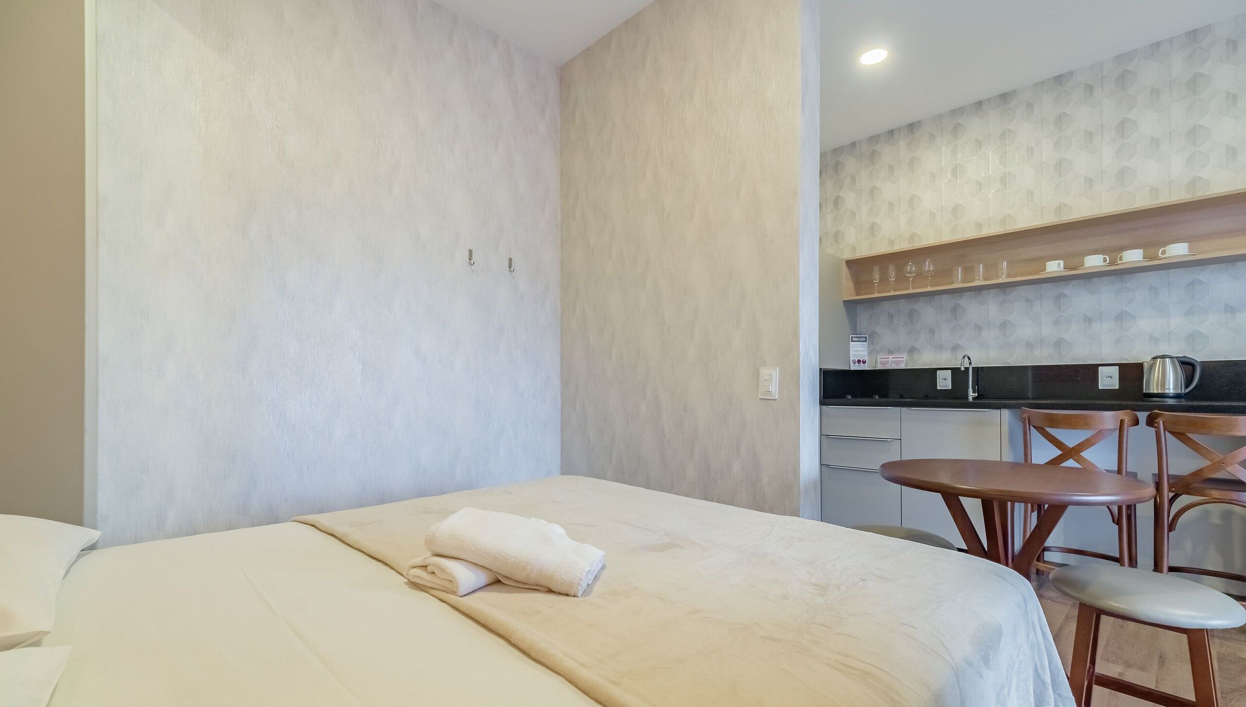 Una habitación de hotel con cama, una pequeña mesa y una zona de kitchenette.