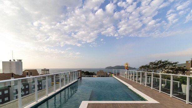 A rooftop infinity pool with a clear view of the sea and distant land under a partly cloudy sky. - Studio w/ Pool nr Beach Bombinhas Vec112 (Bombinhas)