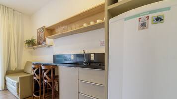 Een kleine keuken met een gootsteen, een koelkast en een houten plank boven het aanrecht.