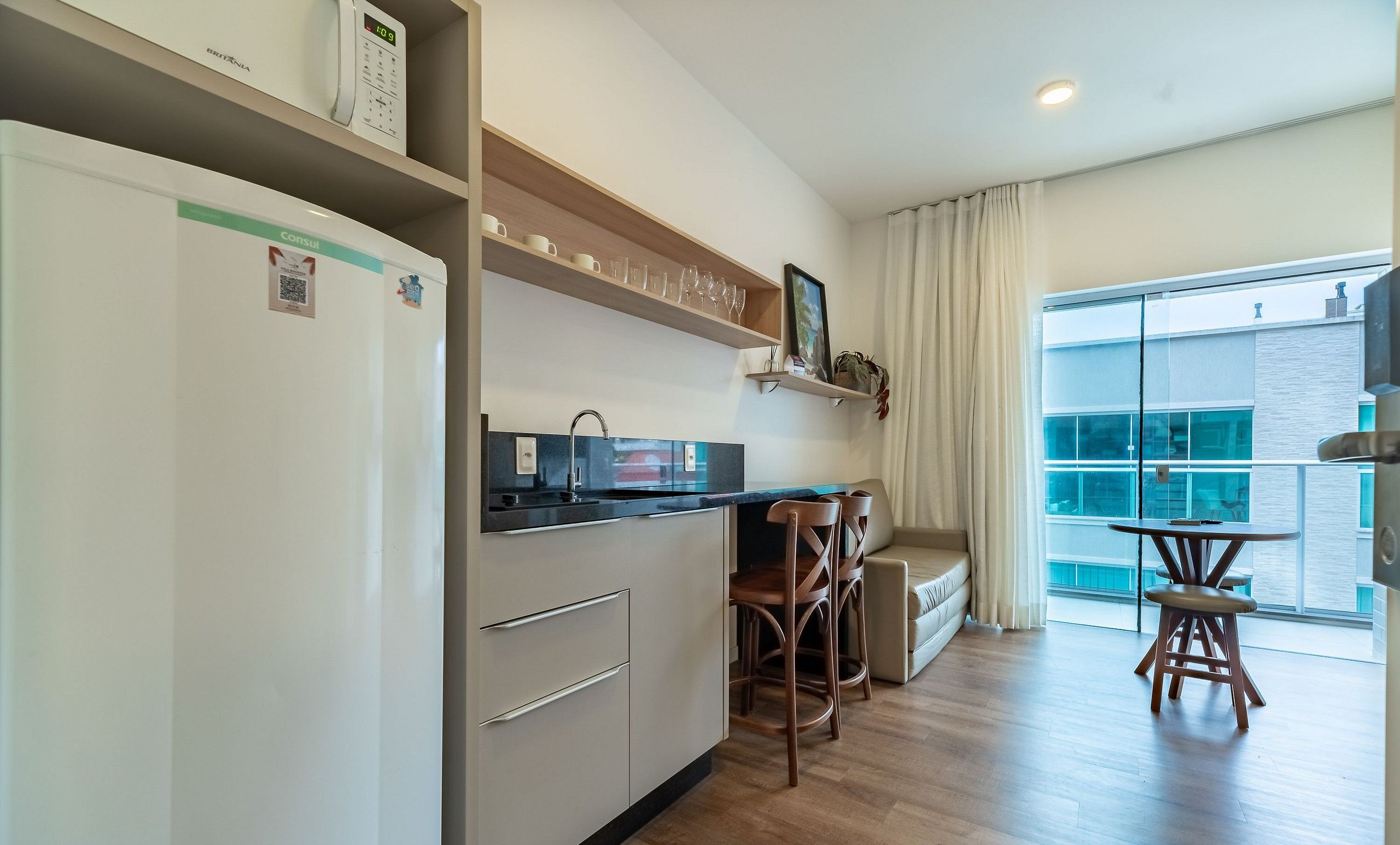 A modern kitchen with a refrigerator, a sink, and a dining area with a table and chairs.
