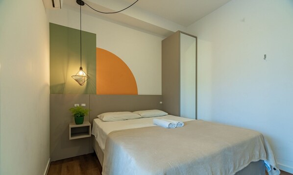 A bedroom with a bed, a bedside plant, a hanging light fixture, and a partial view of a closet. - Studio Pool & Jacuzzi 170m From Sea Vec115 (Bombinhas)