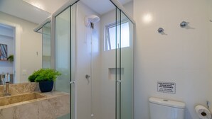 Un baño moderno con cabina de ducha de vidrio, lavamanos de mármol y un inodoro.