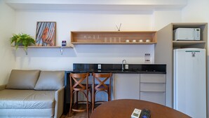 Una kitchenette compacta con microondas, refrigerador y un pequeño comedor con mesa y dos sillas.