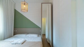 Et soveværelse med seng, spejl og en hængende lampe.
