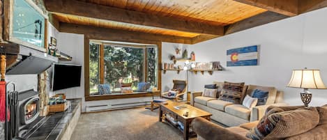 A cozy living room with a fireplace, a sofa, a coffee table, and a television.