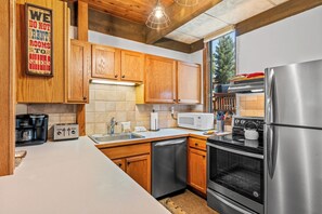 A modern kitchen with wooden cabinets, stainless steel appliances, and a large window. - Cozy 1BR Ski Stay | Fireplace & Winter Shuttle (Steamboat Springs)