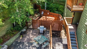 Une terrasse avec un barbecue, des sièges d’extérieur et une clôture en bois.