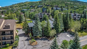 Un quartier résidentiel comprenant plusieurs immeubles, un parking et un paysage montagneux en arrière-plan.