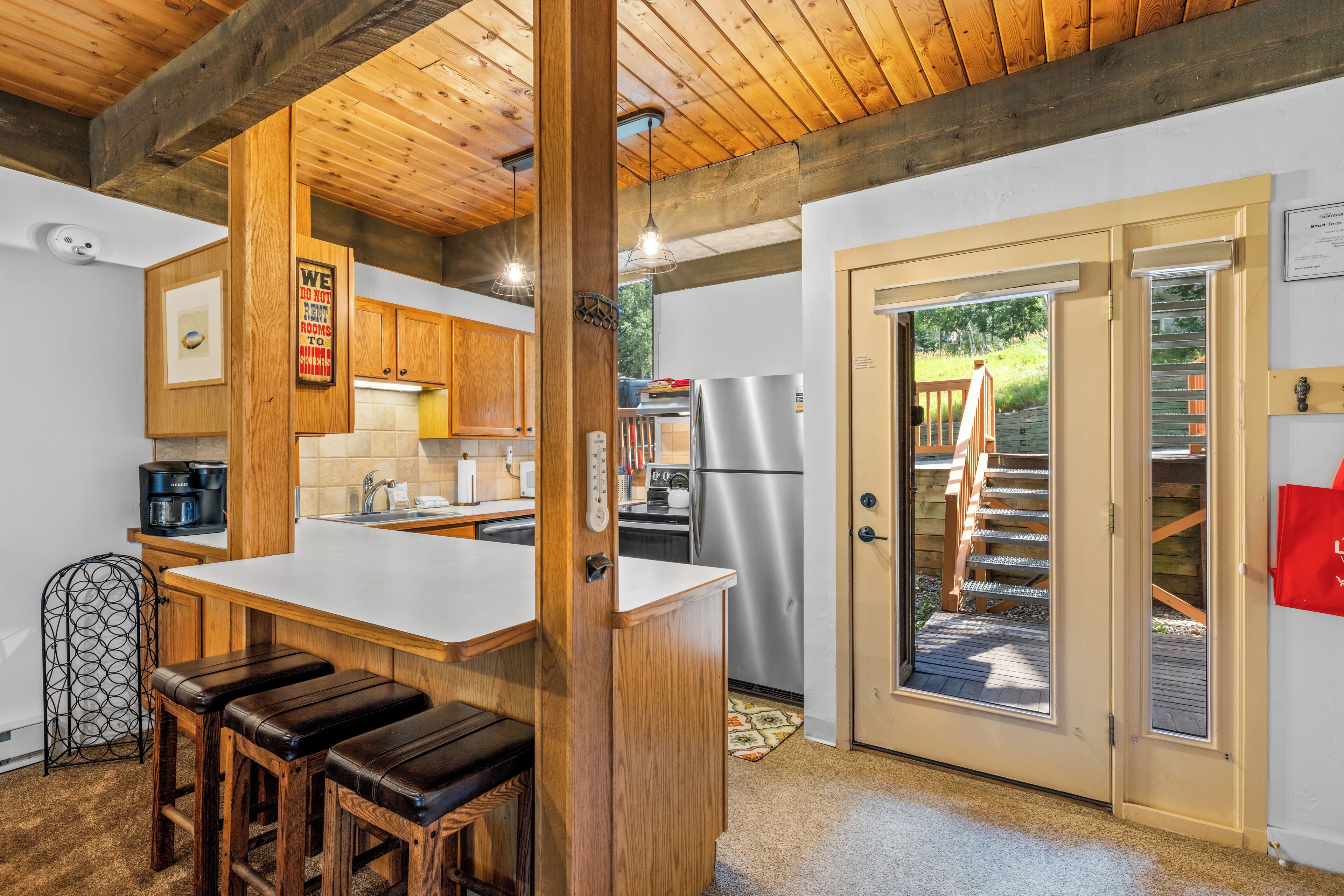 Eine Küche mit Holzausstattung, einem Edelstahlkühlschrank und einer Bar mit Hockern.