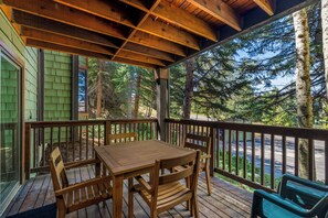 A wooden deck with a table and chairs, surrounded by a railing, overlooking a forested area. - Mountain Comfort at Ski Ranch 103 – Easy Access to Slopes & Town! (Steamboat Springs)